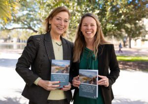 Two women holding the same book that is called navigating the doctorate in education.