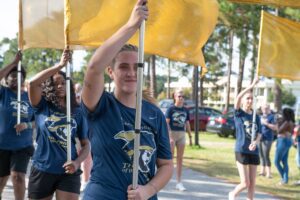 Students are holding a flag that represents the CSU Color Guard marches in the Homecoming Parade in 2021