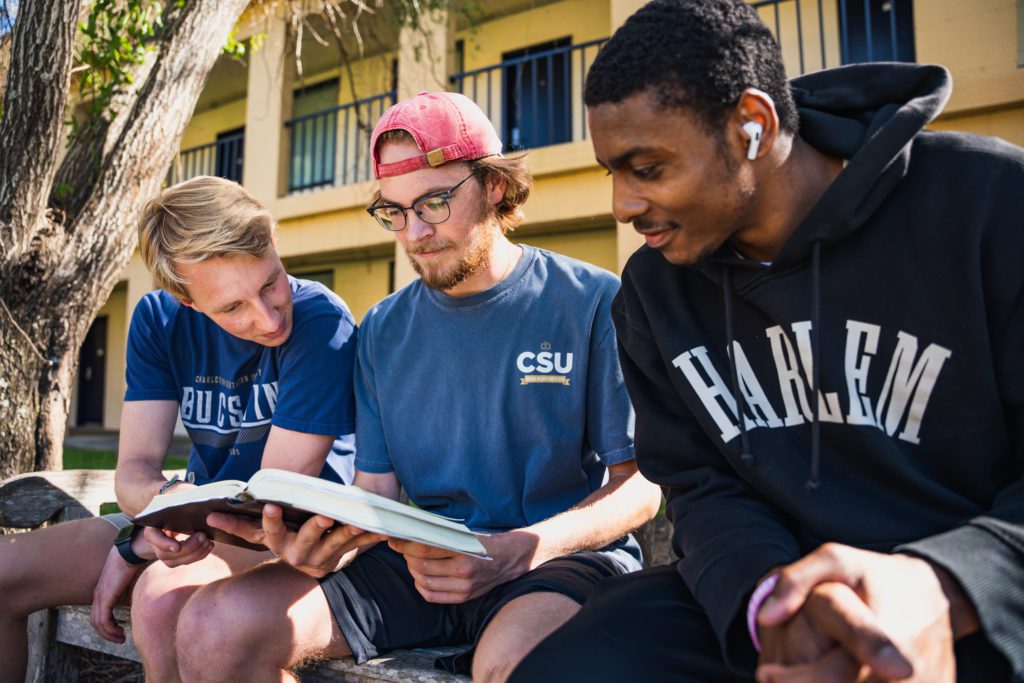 Three boys reading about what the book says