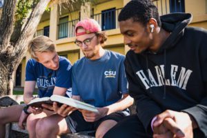 Three boys reading about what the book says