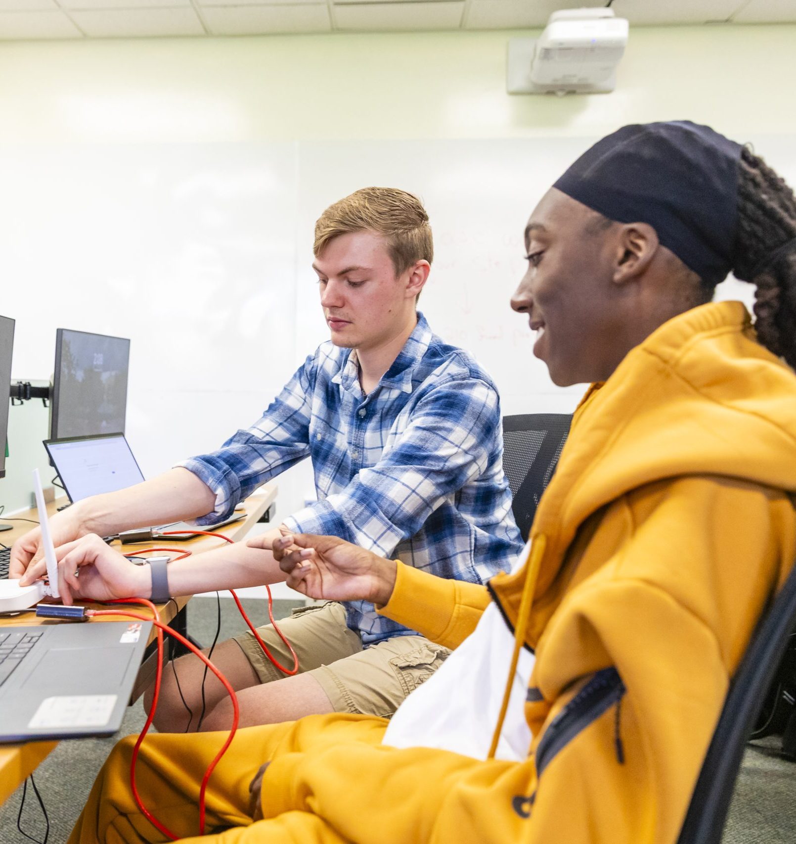 Two male students working in a computer lab together.