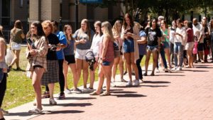 Multiple students on campus are in a line to enter chapel for a student orientation