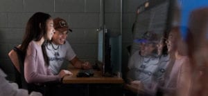 Two students looking at a computer screen in a dark room.
