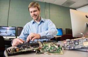Computer parts on a table with a mans hands removing parts.