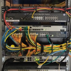 The back of a computer server rack with cables neatly arranged.