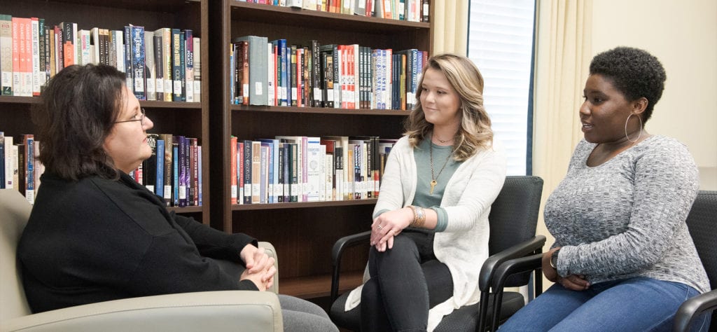 Two students sitting with an couselor peacefully in discussion.