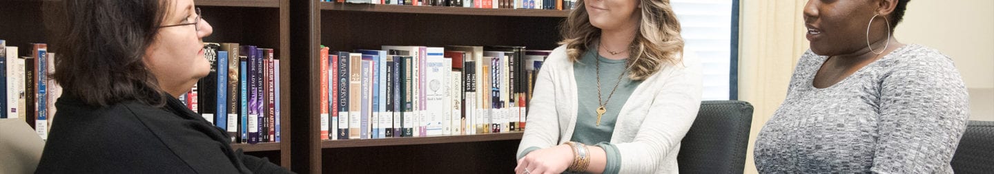 Two students sitting with an couselor peacefully in discussion.