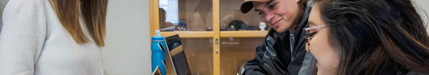 Students in a classroom discussing a math problem with the professor.