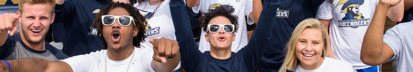 CSU students in the stands of the football stadium cheering with Buccaneers shirts and Go Bucs signs.
