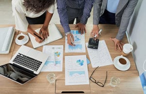 Coworkers analyzing charts and graphs at the meeting, view from above