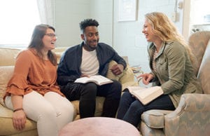 A college minister talking with two college students in a college dorm.