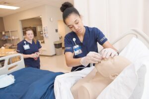 A nursing student inserting an air tube into a mannequin patient