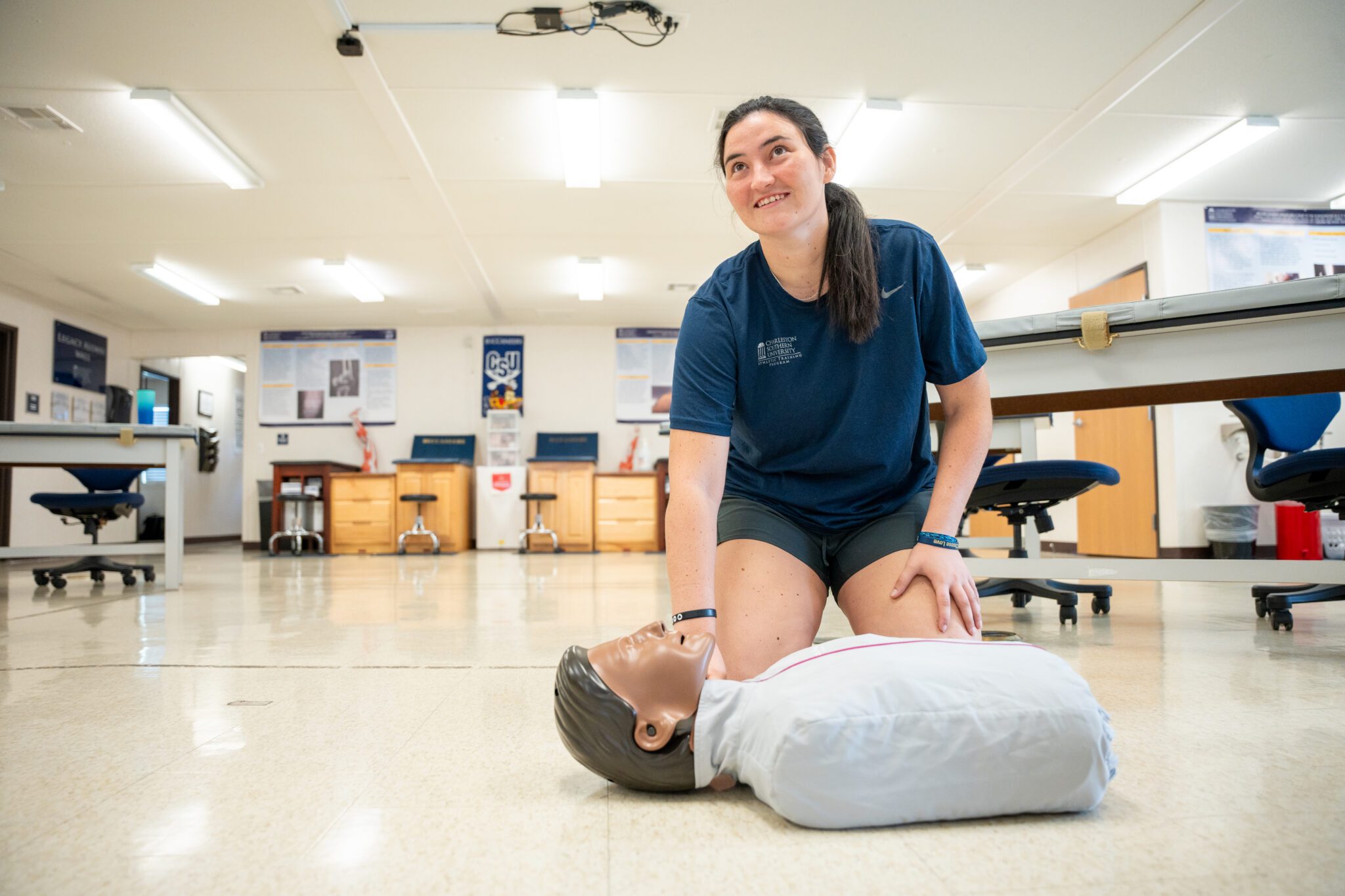 A girl is showing in the athletic training room how to help someone on the ground