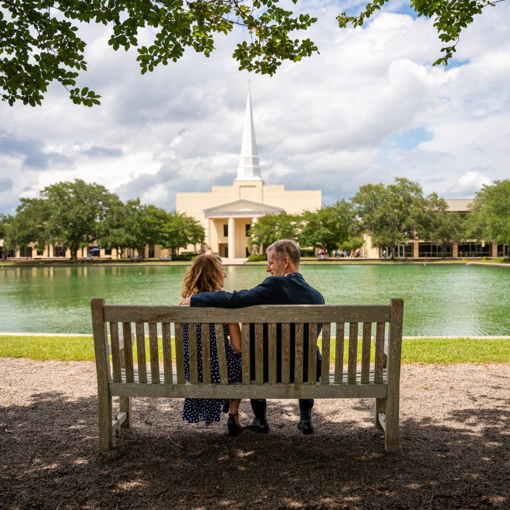 Dr. Costin and his wife sitting on a bench next to the point and in front of chapel