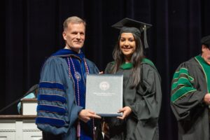 President Dondi Costin presents the diploma to Pooja Viresh Sitapara during the inaugural physician assistant graduation at CSU