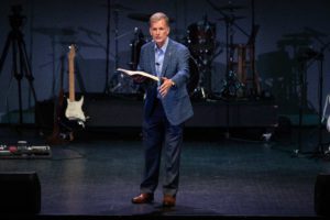 Dr. Costin at Chapel explaining a part of the Bible|Dr. Costin and his wife taking a picture together in his office
