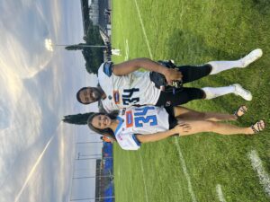 A girl and boy smiling in their football costume number 34 on the football field