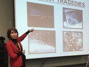 Coroner Rae Wooten at Charleston Southern pointing to images on a projection screen.