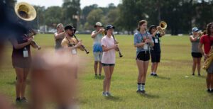 A Marching band praciting outside on the grass